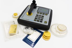 Electronic scale with coins and gold bars for precious metal valuation, highlighting a digital display and keypad surrounded by bullion pieces